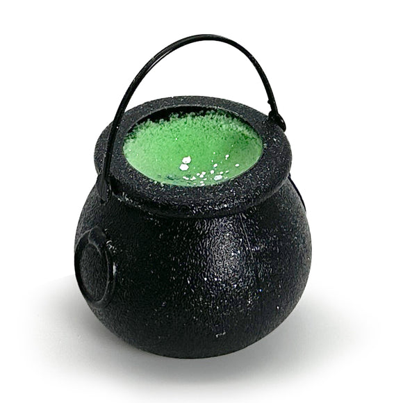Black cauldron with green bath bomb inside on a white background