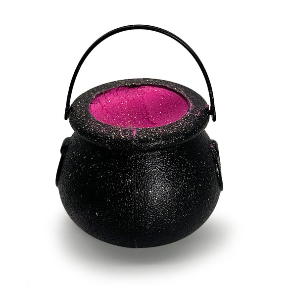 A black bath bomb cauldron with a pink glittery interior.