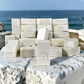 Stack of olive oil soap bars on a stone surface by the ocean.