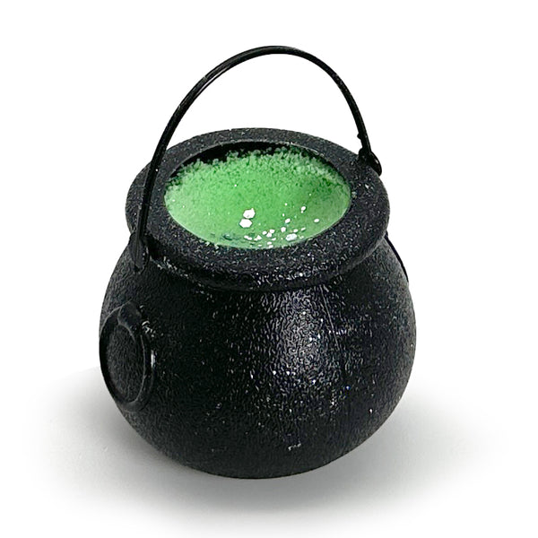 Black cauldron with green bath bomb inside on a white background