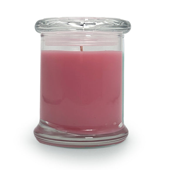 Pink candle in a clear glass jar on a white background