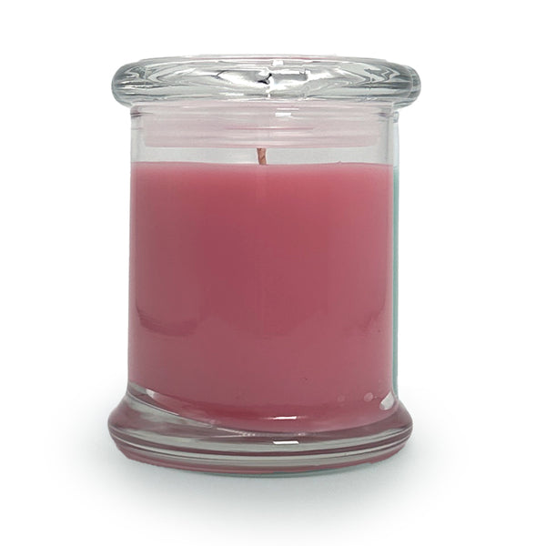 Pink candle in a clear glass jar on a white background