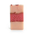 Three-layered soap bar with pink colors and gold accents on a white background