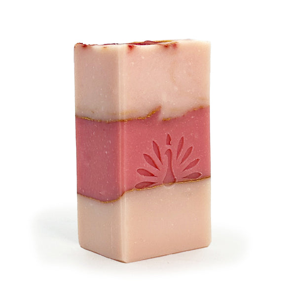 Three-layered soap bar with pink colors and gold accents on a white background