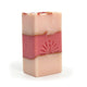 Three-layered soap bar with pink colors and gold accents on a white background