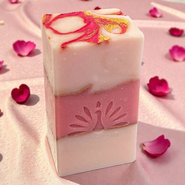 Decorative soap bar with floral design on a pink background with rose petals
