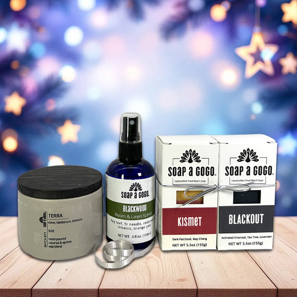 Collection of personal care products including a candle, room spray bottle, and 2 boxed soaps on a wooden surface with a festive background.