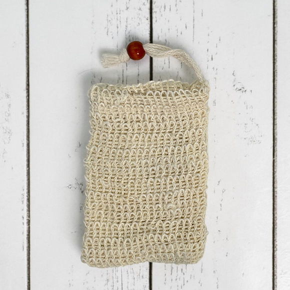 Sisal fiber soap saver pouch with draw string and wooden bead on a white wooden surface