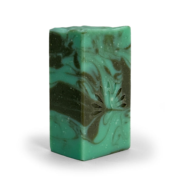Side view of green and gray swirled soap bar with with peacock logo on a white background