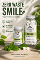Two glass jars of Soap A GoGo Toothpaste Bites in Mighty Mint, displayed on a wooden surface with fresh mint leaves. The background features a warm, sun-dappled texture with green leaves, and the left side contains product feature icons and text.