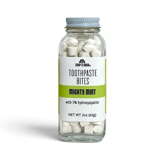 A clear glass jar of Soap A GoGo Toothpaste Bites in the Mighty Mint flavor, filled with white toothpaste bites and topped with a metal lid, set against a plain white background.