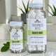 Two clear glass jars of Soap A GoGo Toothpaste Bites in Mighty Mint flavor, one small and one large, with white toothpaste bites visible inside and mint leaves on a light marble surface.