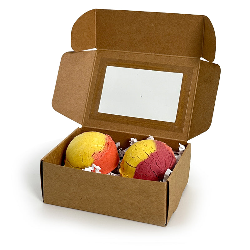 Open cardboard box containing two colorful bubble bath truffles on a white background