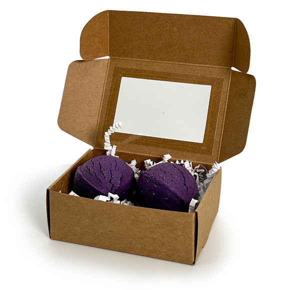 Two blue bubble bath truffles in a cardboard box on a white background
