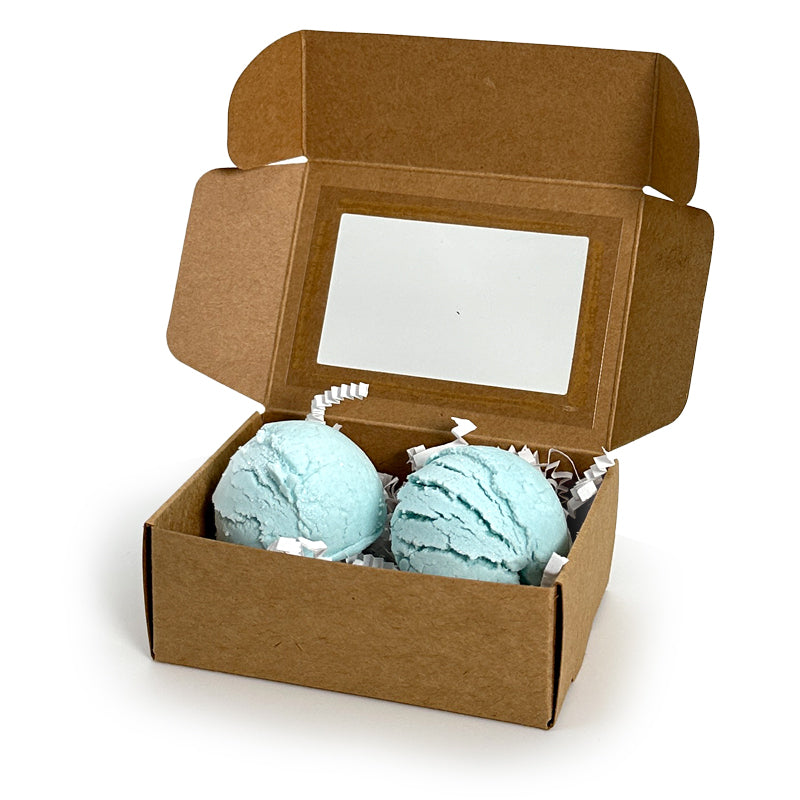 Two blue bubble bath truffles in a cardboard box on a white background