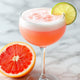 a half grapefruit and Paloma cocktail on white marble