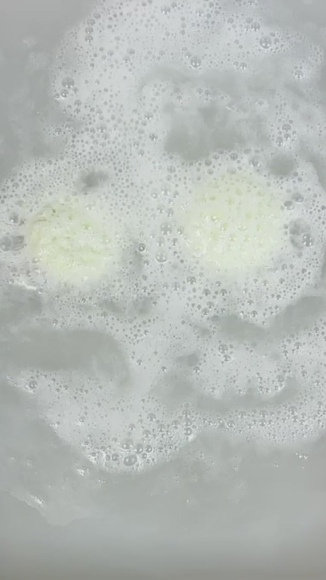 Coconut lime macaron bath bomb in a tub
